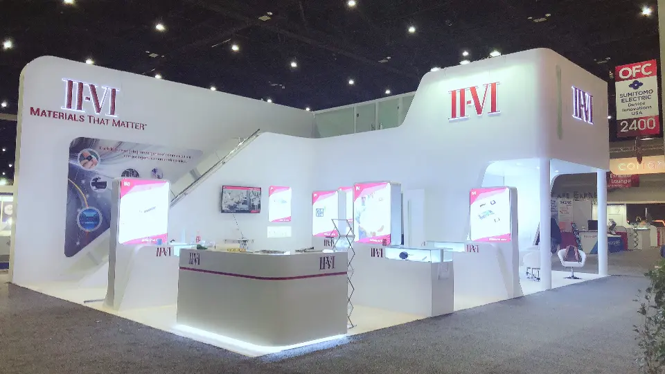 Wide view of the white angular booth with backlit graphics and long counter
