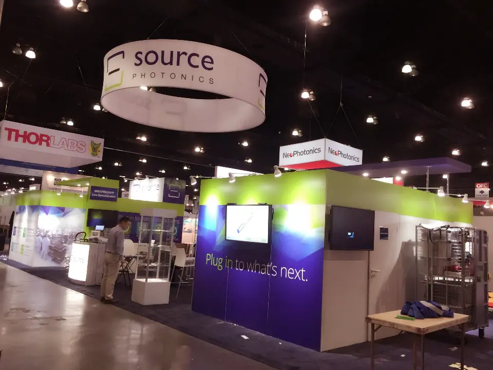 Aisle view of the enclosed purple booth with green top edge and corner logo panel
