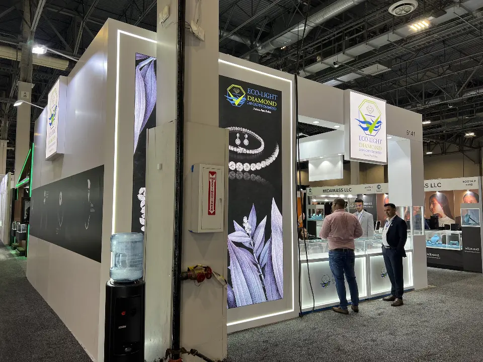 Outer wall of the Eco-Light booth with backlit bracelet graphic and staff meeting a visitor