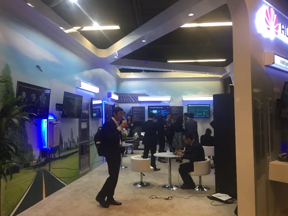 Booth interior with visitors, white stools, mural and a blue-lit side wall