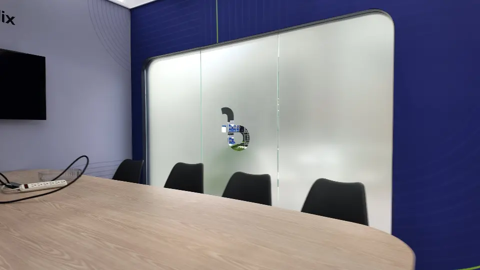 Meeting table with black chairs facing the frosted glass wall