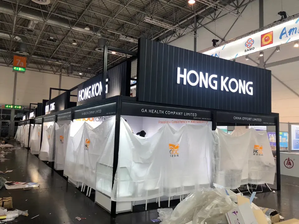 Long row of black-frame shell booths draped in white covers below the pavilion header