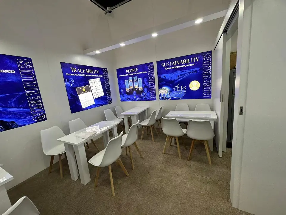 Meeting room corner with backlit graphics above white tables and chairs