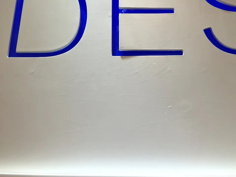 Detail of large blue letters mounted on a white wall panel