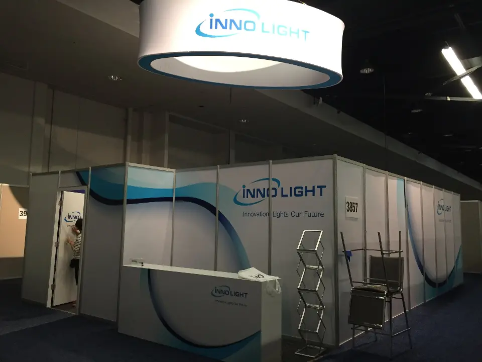 Open corner with a white reception counter, brochure rack and round INNOLIGHT sign