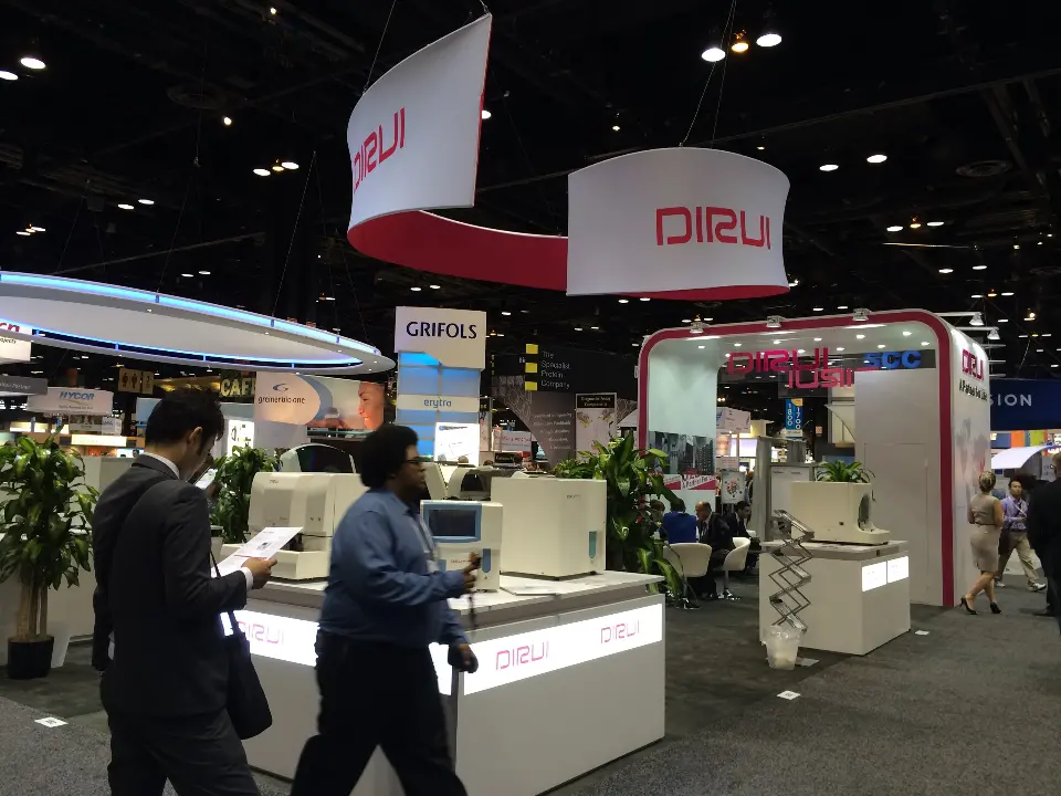 Show-day view of visitors walking past DIRUI counters and the curved hanging band