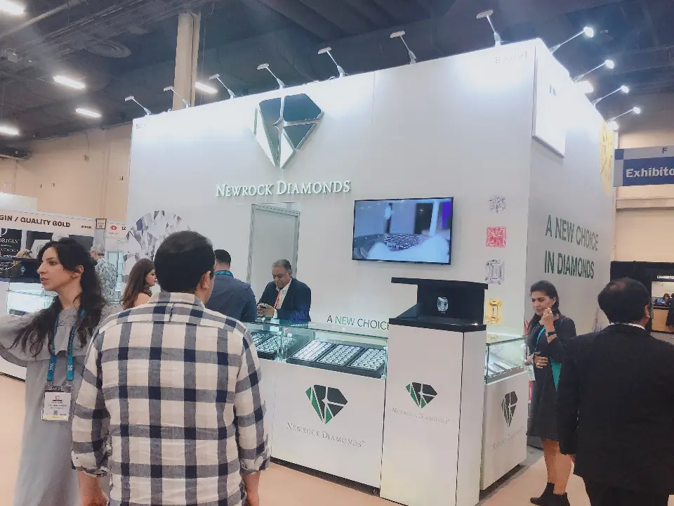 Wider view of the Newrock Diamonds booth with attendees browsing the jewelry showcases