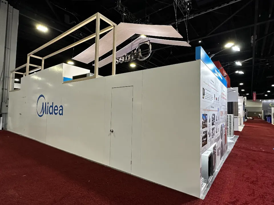Rear side of the Midea stand showing a long white wall with blue Midea logo and storage door