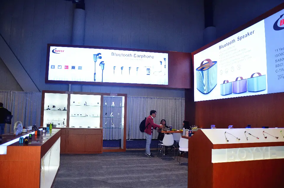 Inside the BOYYE stand, lit glass cabinets and a small meeting table beneath the earphone lightbox
