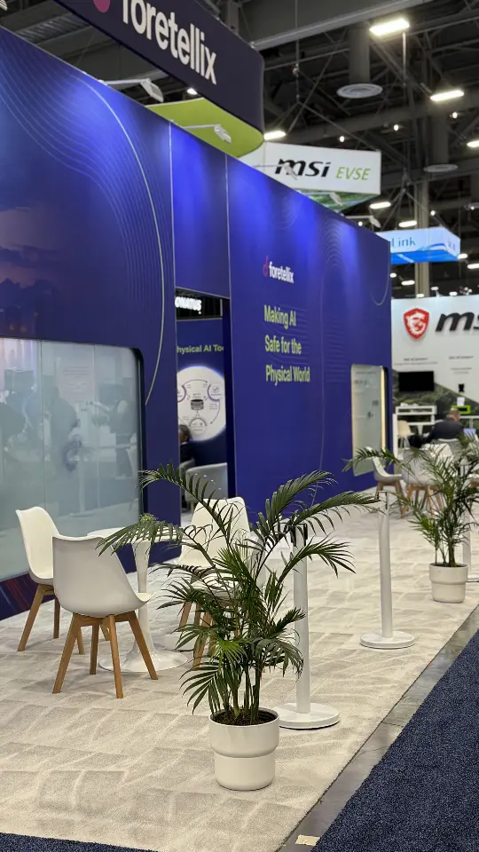 Booth corner with palm and chairs near the aisle