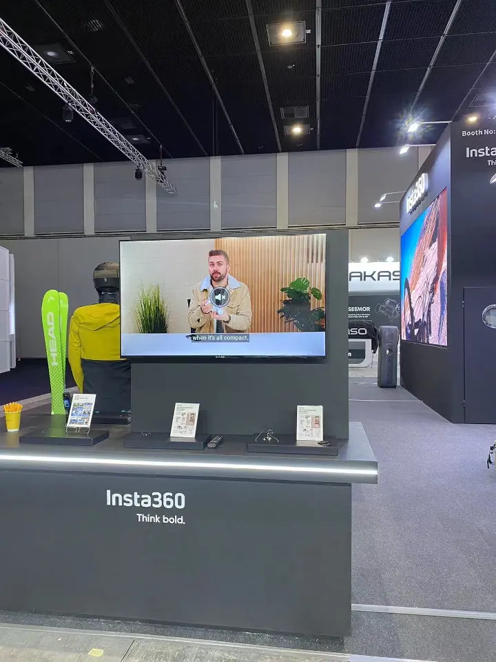 Demo counter with a lit Insta360 front panel facing a screen on a black wall