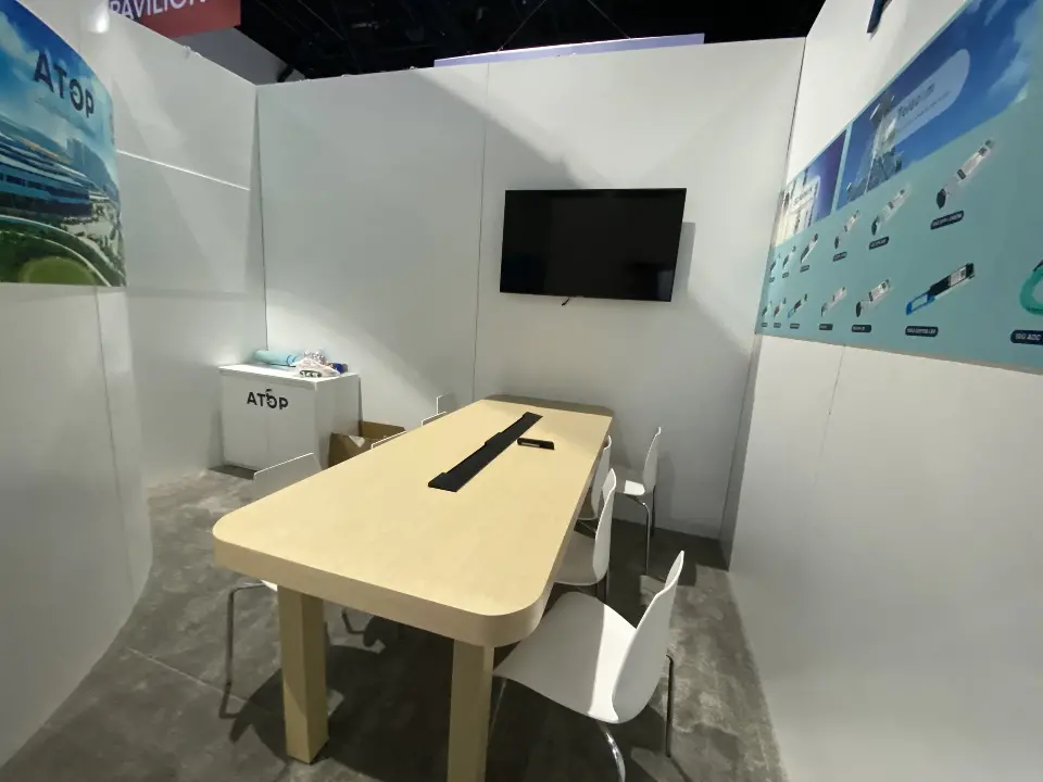 Meeting room with a wood-look table, white chairs and wall screen