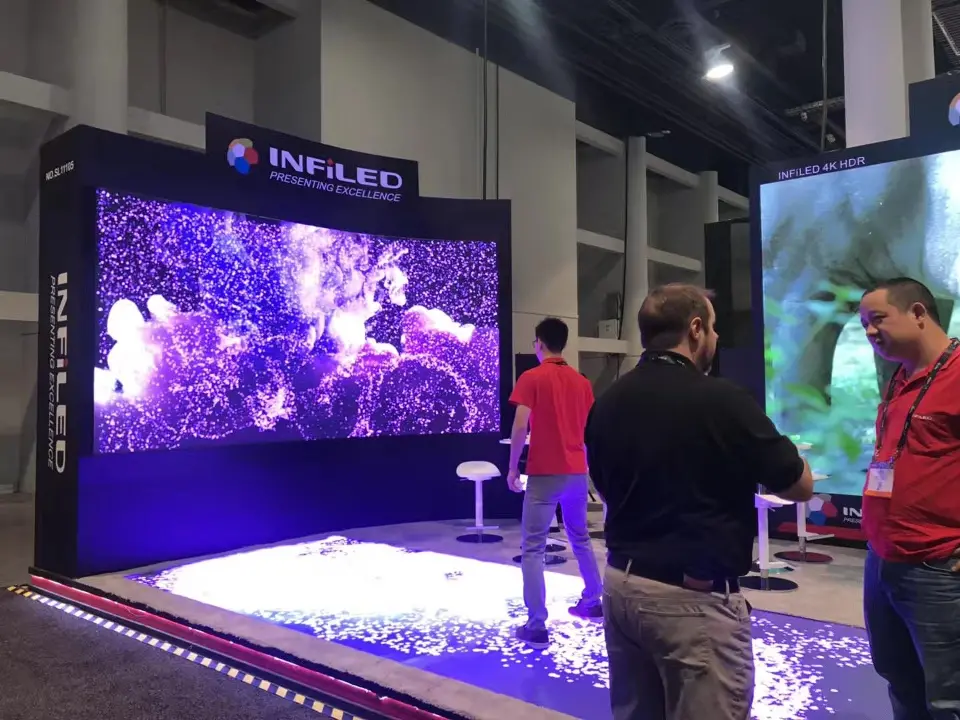 Purple-toned video screen and glowing floor display with visitors at the edge