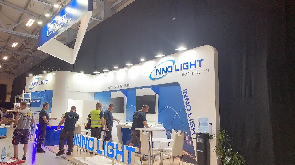 Side angle of visitors talking at display tables beside the blue wall graphics