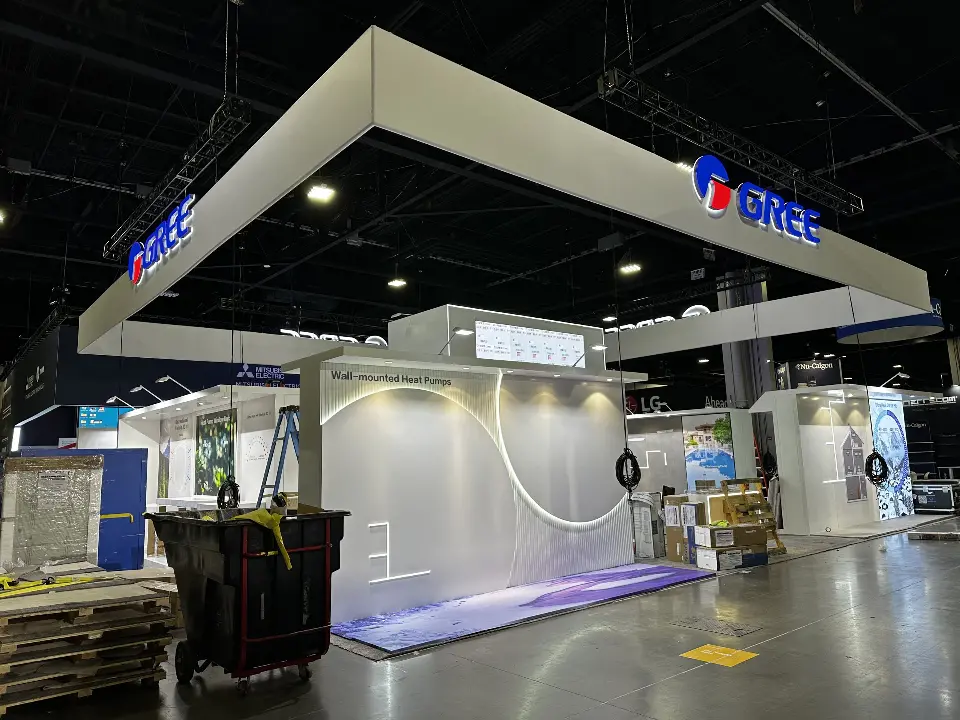 During installation: GREE booth under white square header with pallets on bare floor