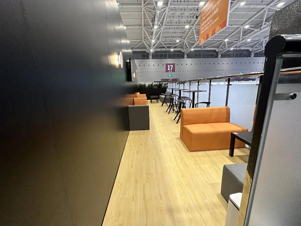 Lounge with orange sofa and wood-look floor behind a glass rail