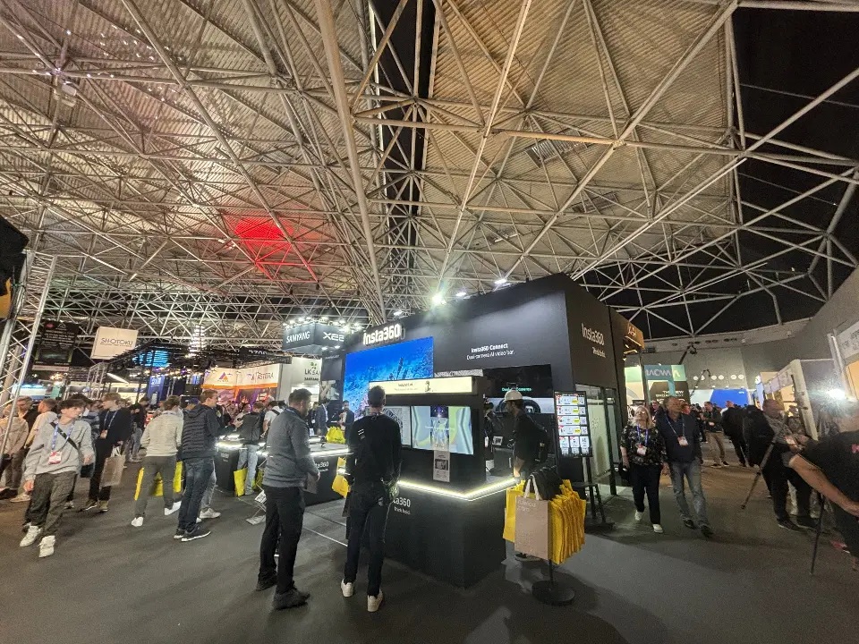 Aisle view of the booth with graphic walls and visitors testing cameras