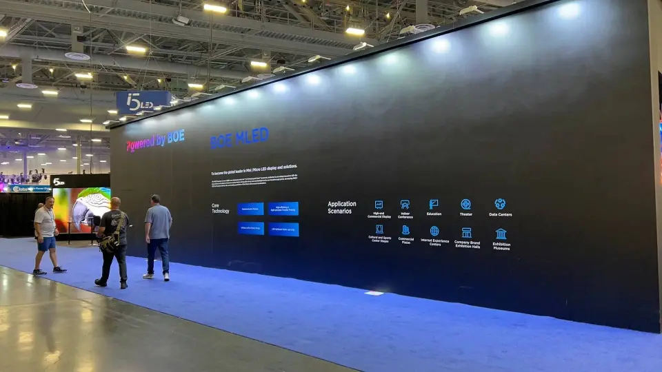 Long black wall with a row of small product screens over blue carpet