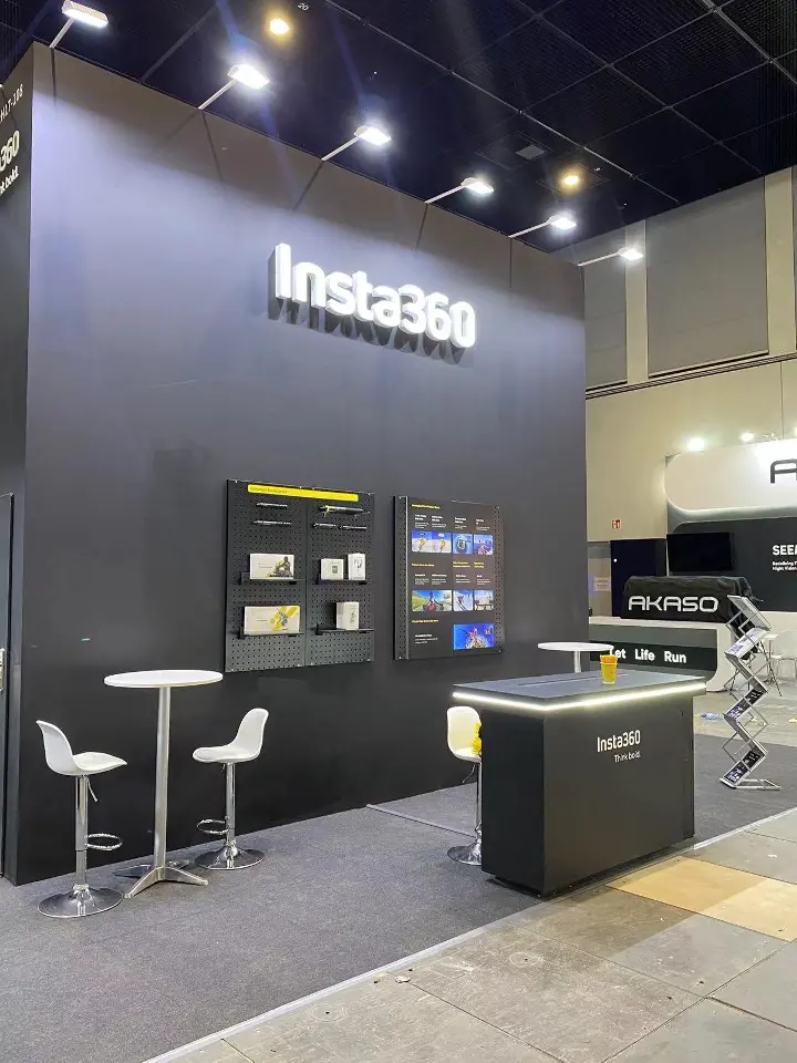 Corner of the stand with product shelves, white bar stools and a lit counter