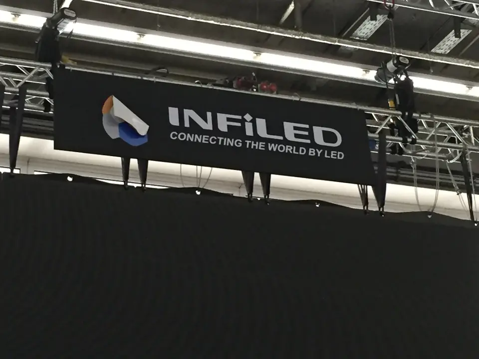 Black hanging banner with the INFiLED logo above a dark screen wall