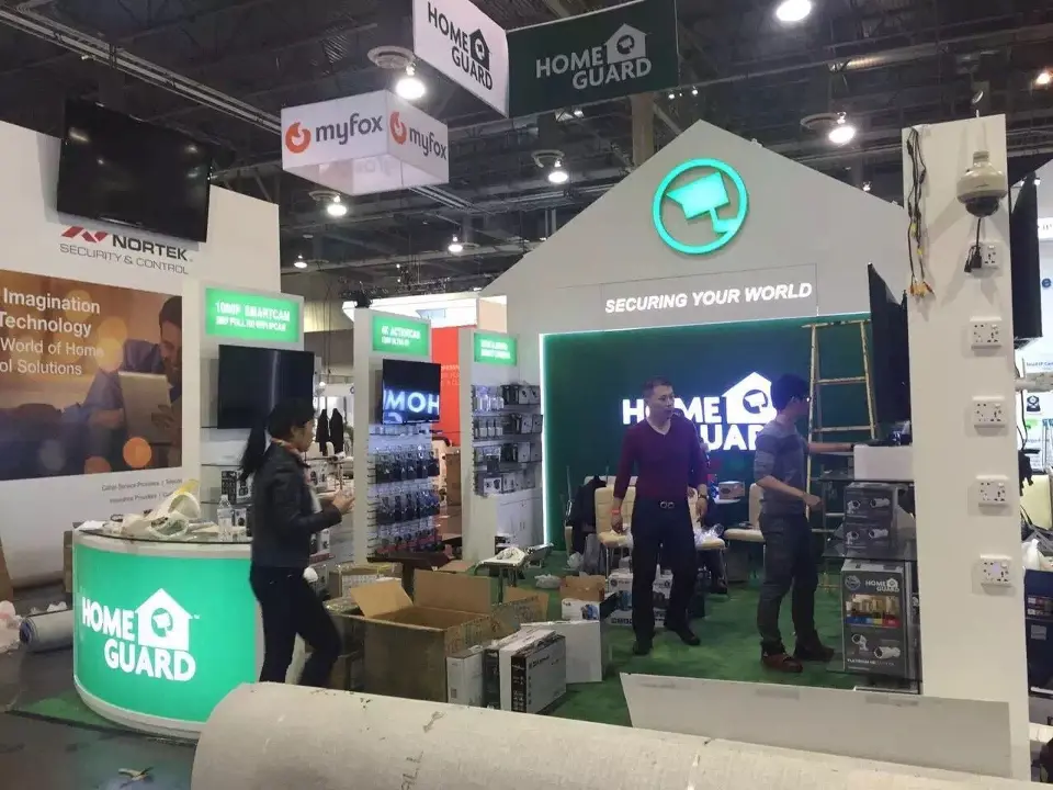 Green house-gable booth with HOME GUARD logo wall and round green counter