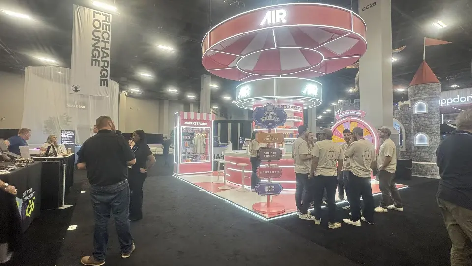 Visitors gathered around the AIR carnival booth under the pink ring sign