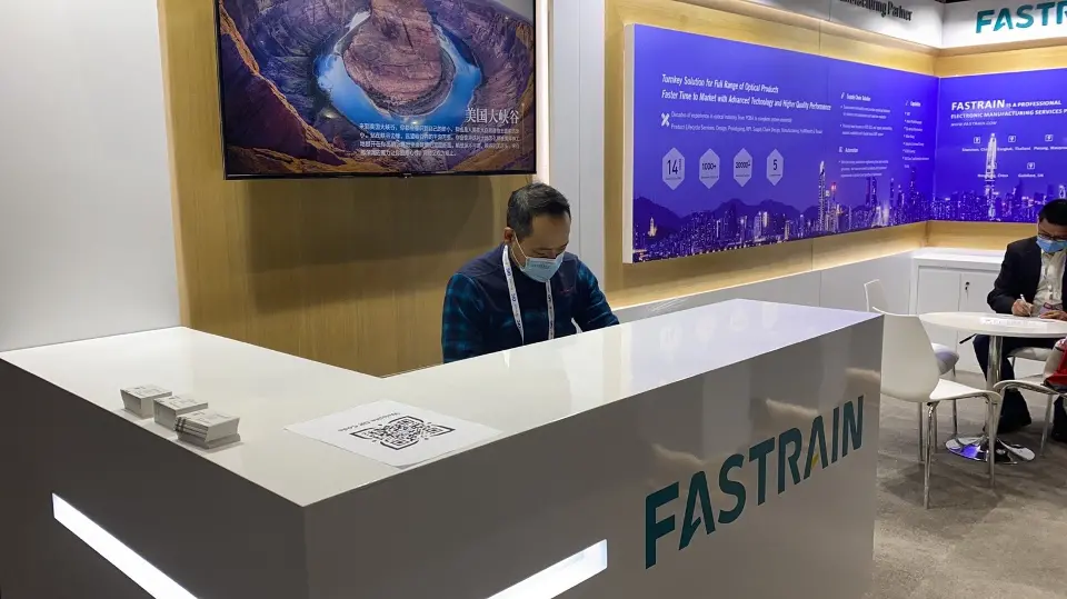 Staff member seated behind the counter in front of the purple graphic wall