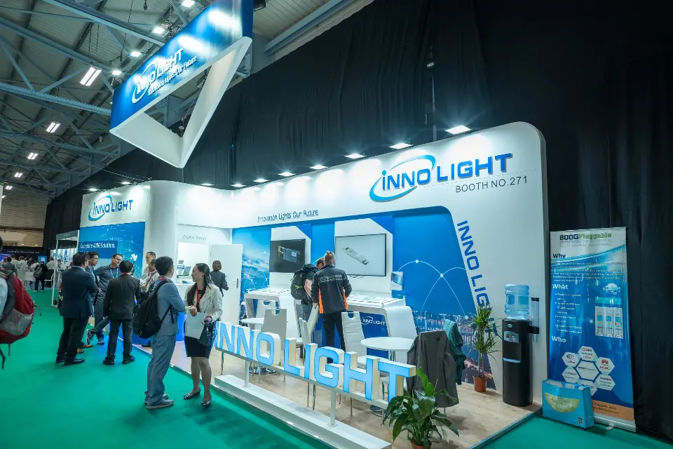 Wide view of angled InnoLight canopy and blue walls with visitors on green carpet