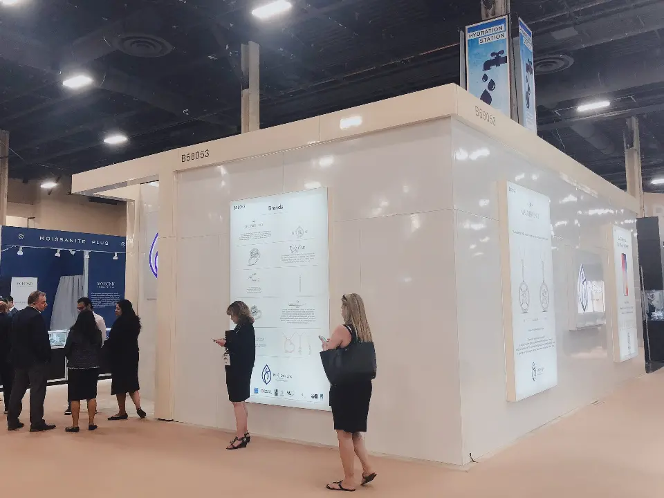 Glowing white side wall with a tall backlit graphic and visitors nearby