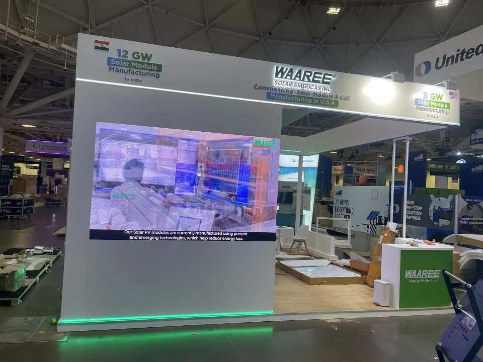Large video screen on the aisle wall below the WAAREE Solar Americas header