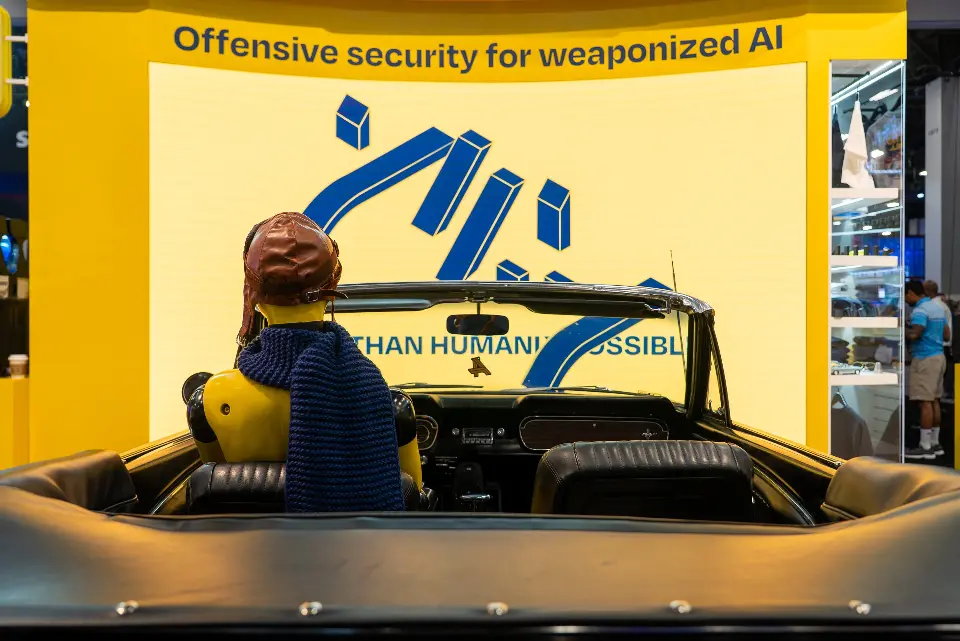 Driver's seat view of the figure in an aviator cap facing the Offensive security for weaponized AI wall