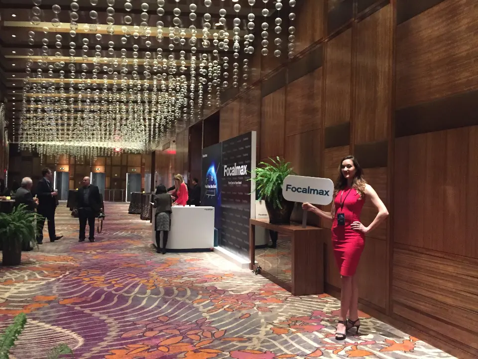 Hotel corridor with a Focalmax display wall, white counter and host in red dress