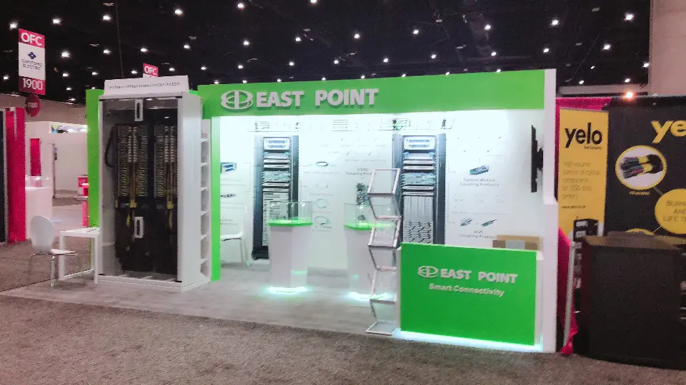 Front view of white back wall with cable products, screen and green logo counter