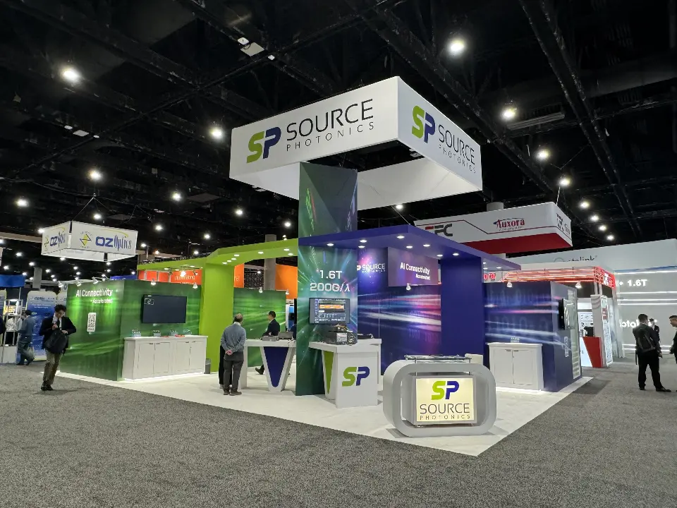 Rear corner with a white demo kiosk and dark blue panels below the cube sign
