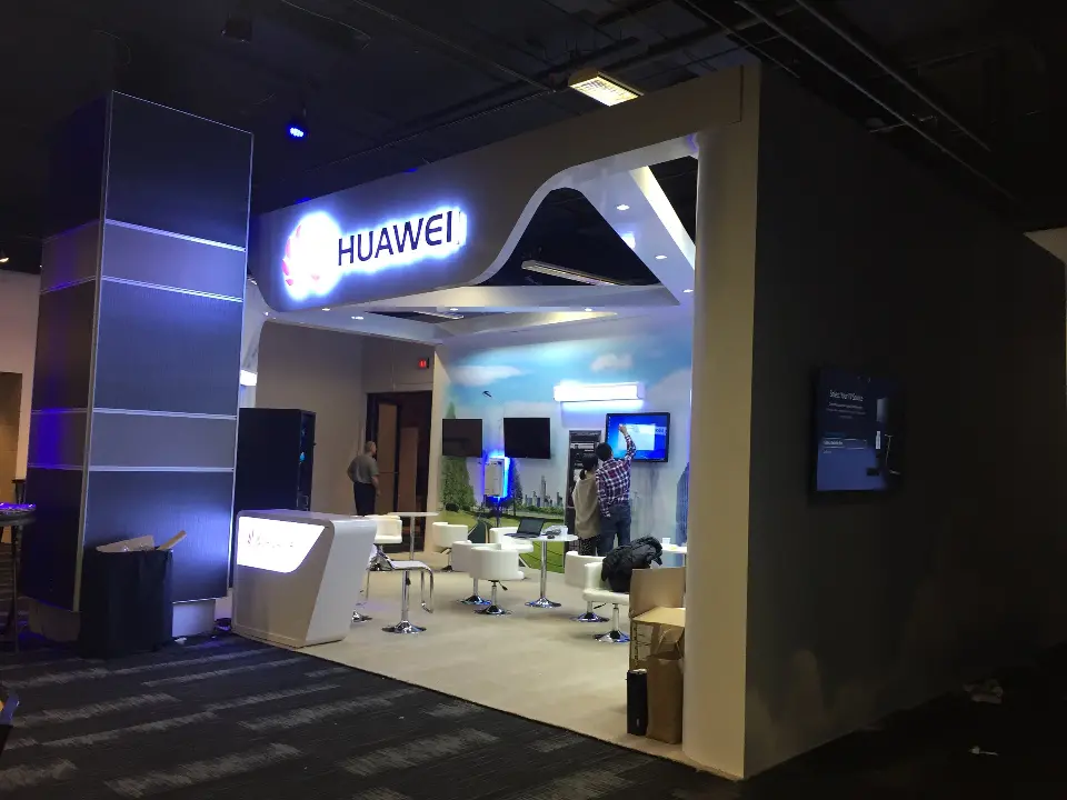 Finished Huawei booth corner with lit logo, white arch and blue accent lighting
