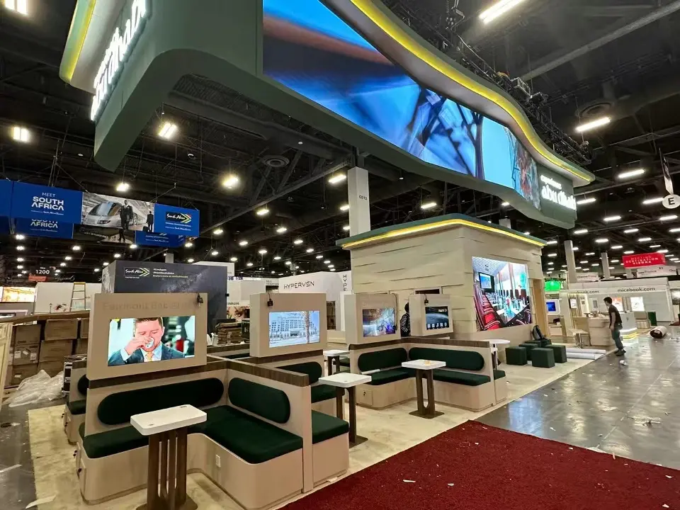 Experience Abu Dhabi meeting pods with green upholstered booths and screens beneath the curved green canopy