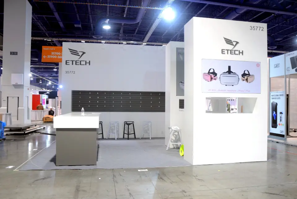 Empty open booth with a tall white ETECH tower and grey counter before opening