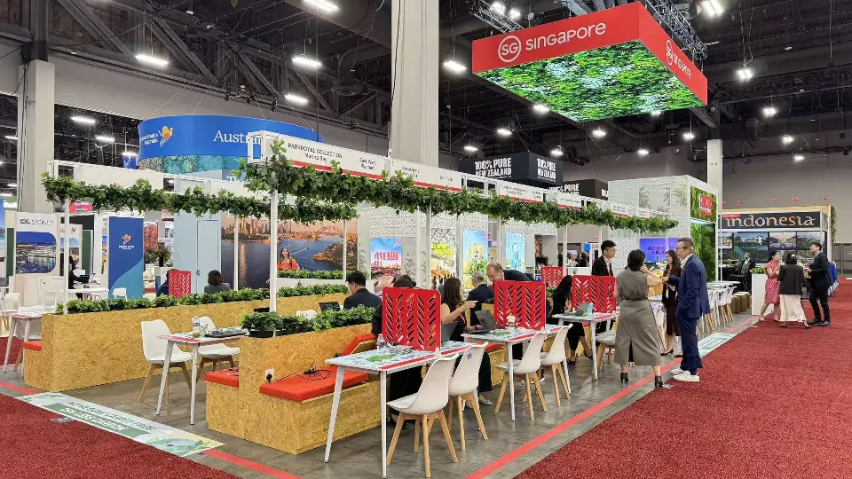 Long row of meeting tables, red bench cushions and green garlands overhead