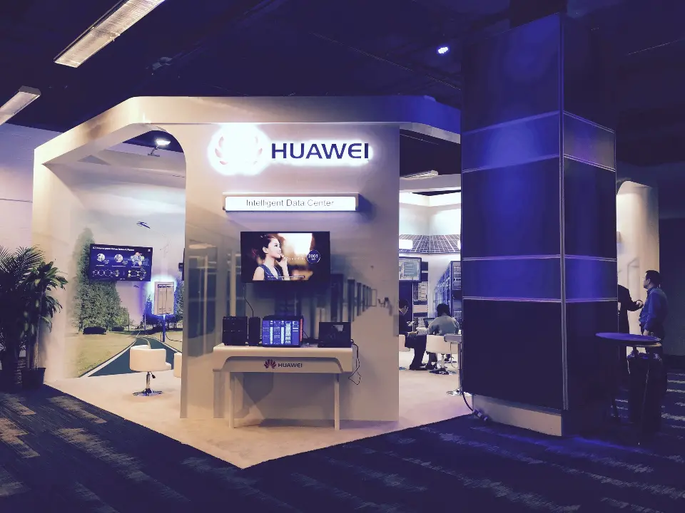 Corner view of the white Huawei arch with a screen, display table and plants