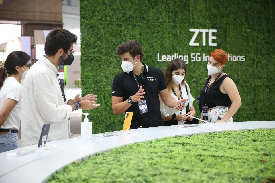 Staff speaking with guests in front of a green wall with ZTE branding