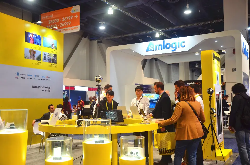 Visitors at the round yellow counter with camera rigs and the back wall