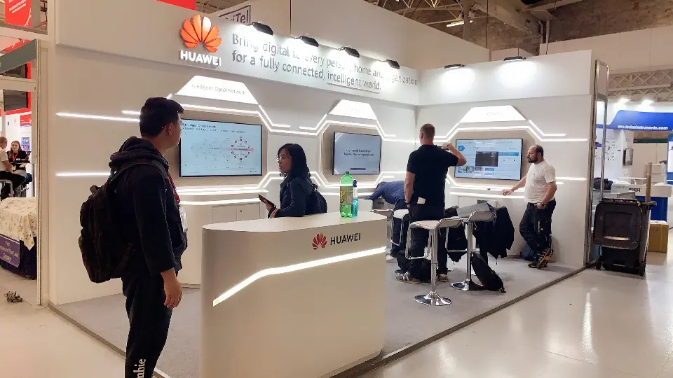 Visitors talking in front of the white wall with light lines and hexagonal video screens