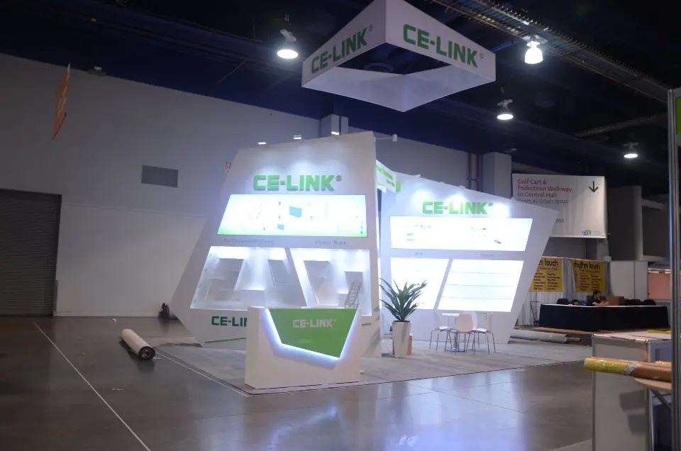 Finished CE-LINK booth lit up under its square hanging sign in a quiet hall