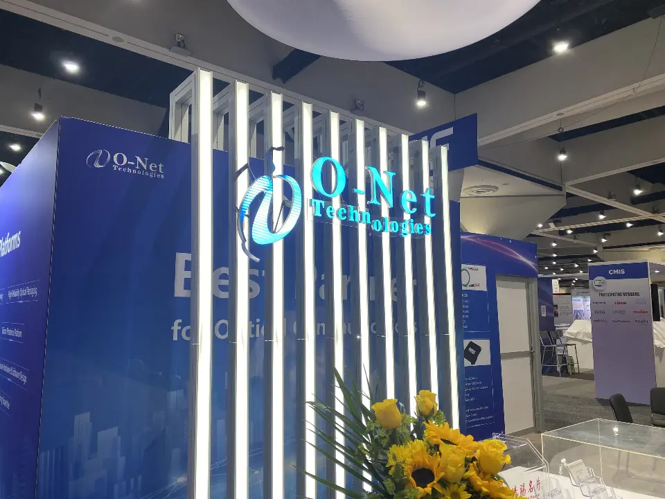 Angled view of the slat logo wall and navy side panel with flowers in the foreground