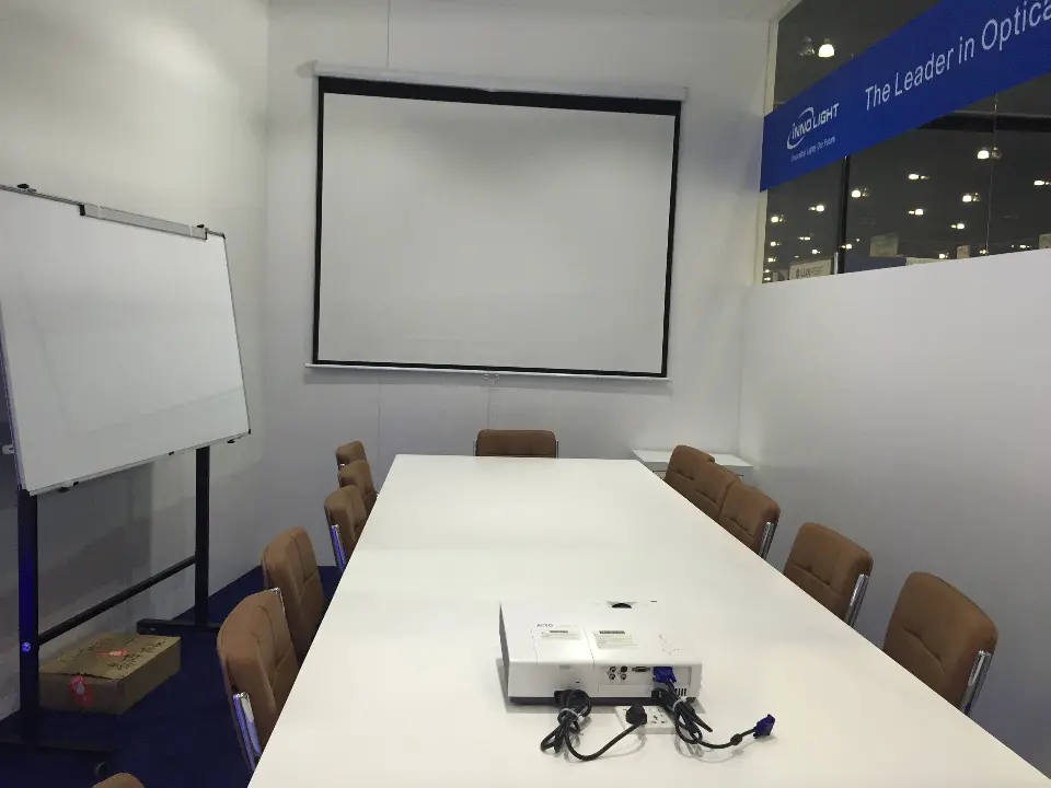 Meeting room with white table, chairs and pull-down projection screen