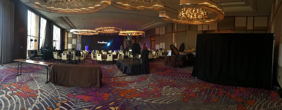 Panoramic view of the ballroom with stage, tables and draped equipment