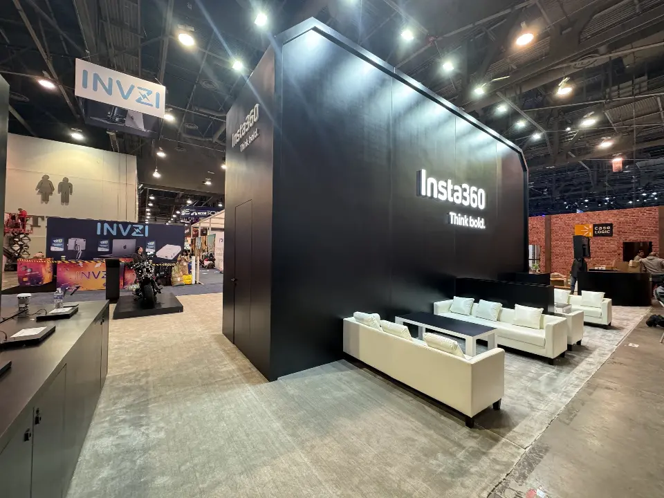 Black wall with the logo beside a lounge with white sofas