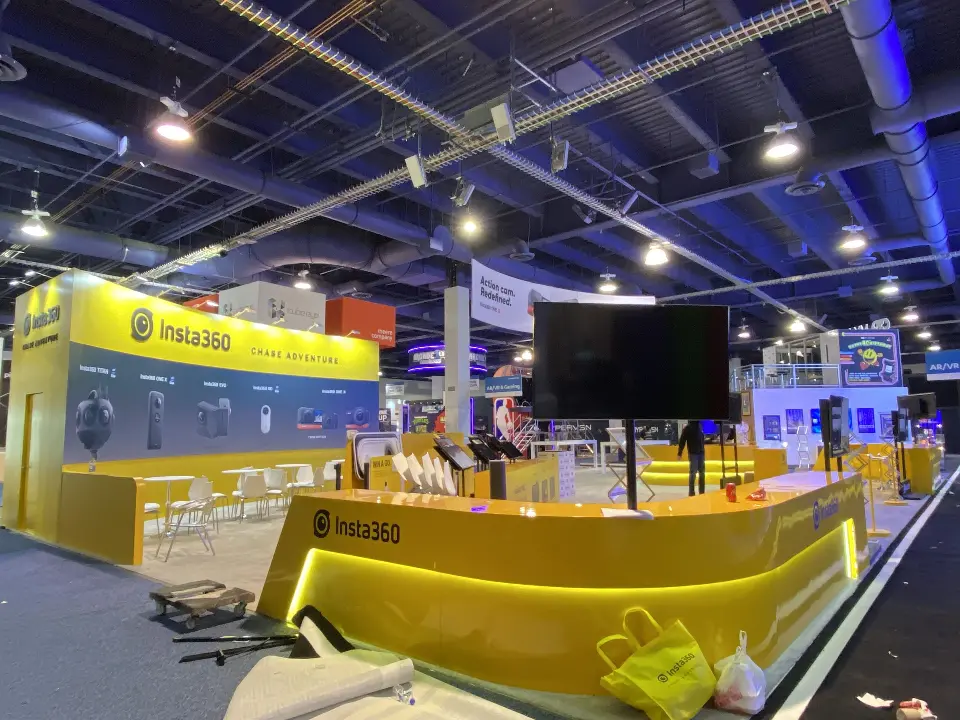 Curved yellow counter with Insta360 logo and screens on poles, nearly finished