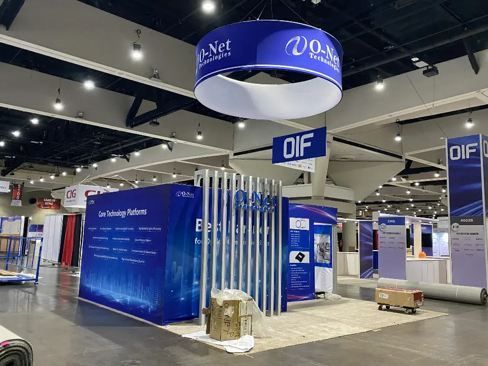 Wide view of the navy O-Net booth with blue ring sign and white lit vertical slats