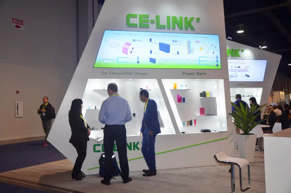 Visitors in front of the backlit CE-LINK display wall beside a stool
